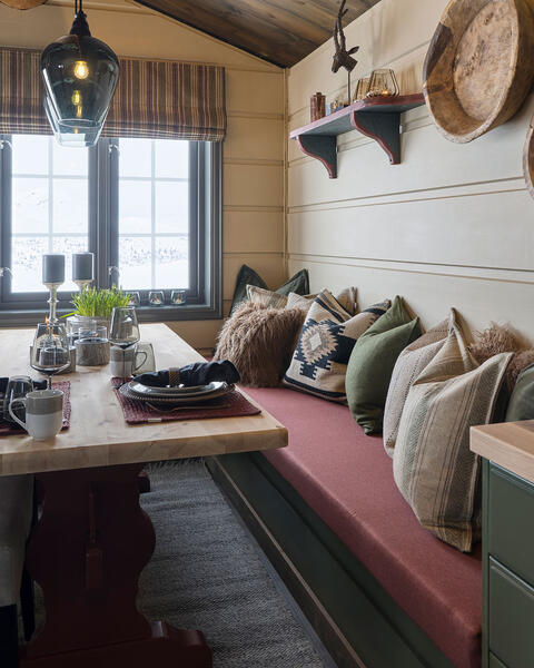 Koselig benk på kjøkkenet med grove pynteputer som er fylt med innleggsputer som vi har produsert her på Mysen.  Putene inneholder akkurat passe fjær slik at de ikke bare ser lekre ut, men også gir god støtte i ryggen. 